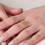 Gold butterfly ring on woman's hand with elegant manicure, showcasing delicate jewelry design.