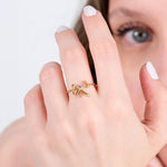 Elegant gold bow ring with gemstone on woman's hand, close-up view, stylish jewelry accessory.