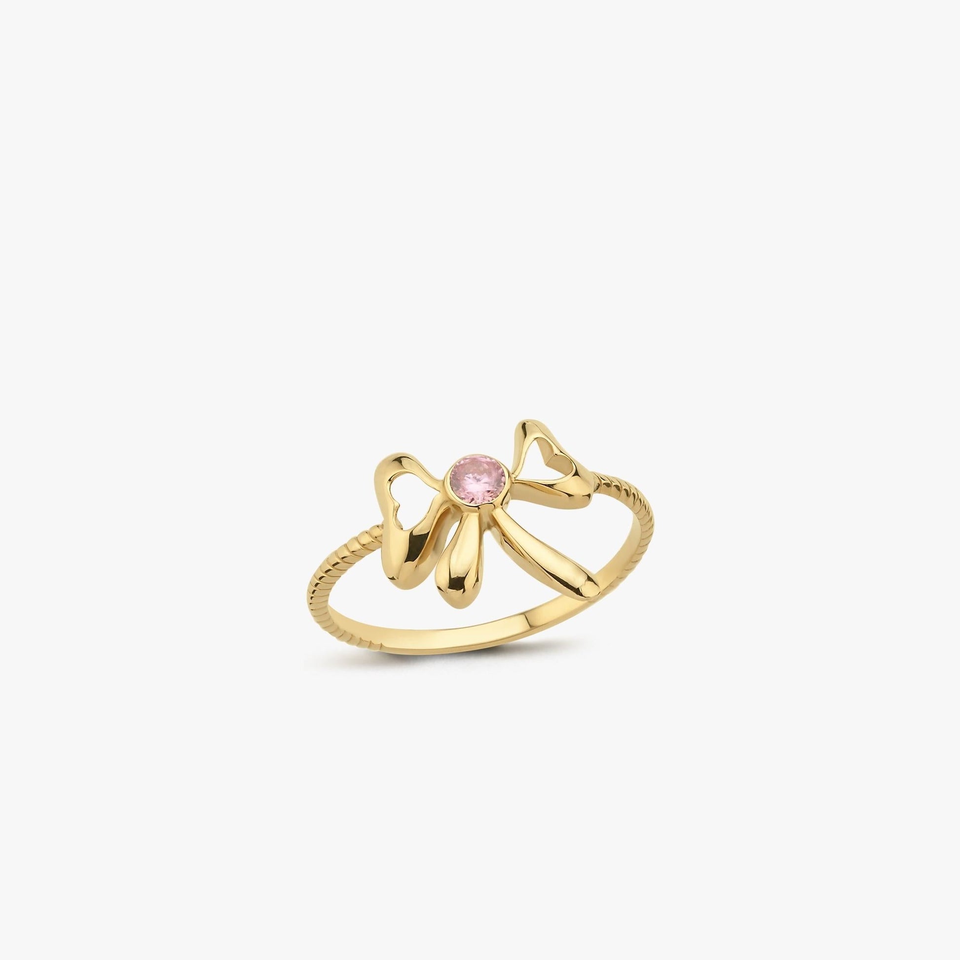 The Mionza Bow Ring in 14K Solid Gold showcases a delicate bow design adorned with a pink gemstone set at its center. The band's textured pattern enhances the overall elegance of this knot love ring, all highlighted against a plain white background to emphasize the intricate details.
