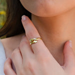Close-up of a woman's hand wearing a unique gold ring with interlocking hands design.