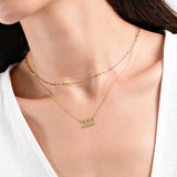 Close-up of layered gold necklaces featuring a '222' pendant on a woman's neck.