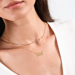 Close-up of woman wearing elegant gold layered necklaces, showcasing minimalist jewelry fashion.