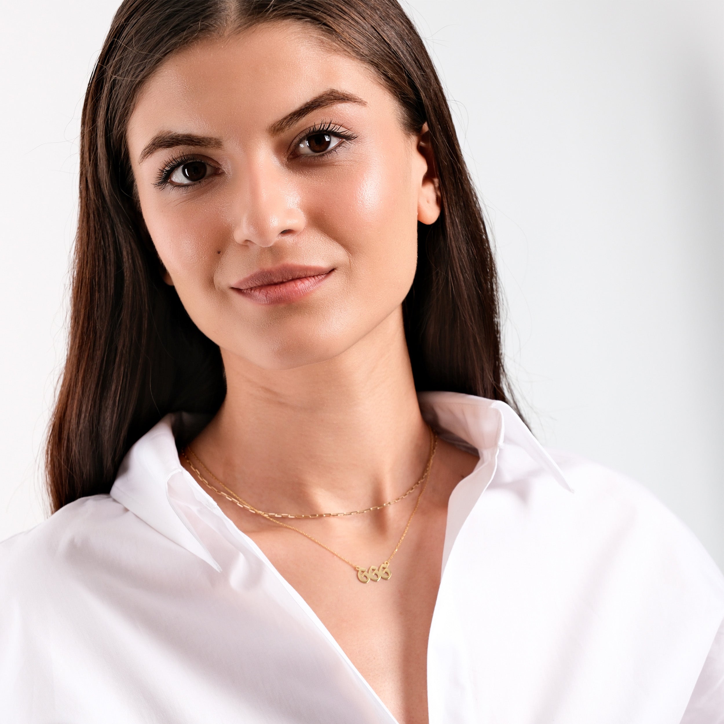 Woman in white shirt wearing delicate gold necklace, showcasing elegance and minimalist jewelry style.