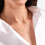 Woman wearing elegant gold necklaces on white shirt, minimalist jewelry fashion.