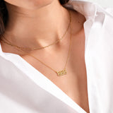 Woman wearing layered gold necklaces over a white blouse, showcasing elegance and minimalistic fashion style.