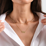 Woman wearing layered gold necklaces over white shirt, showcasing elegant jewelry style and fashion.