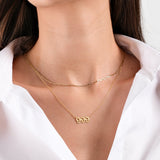 Elegant gold necklace with "999" pendant on woman wearing a white shirt, showcasing minimalistic jewelry style.