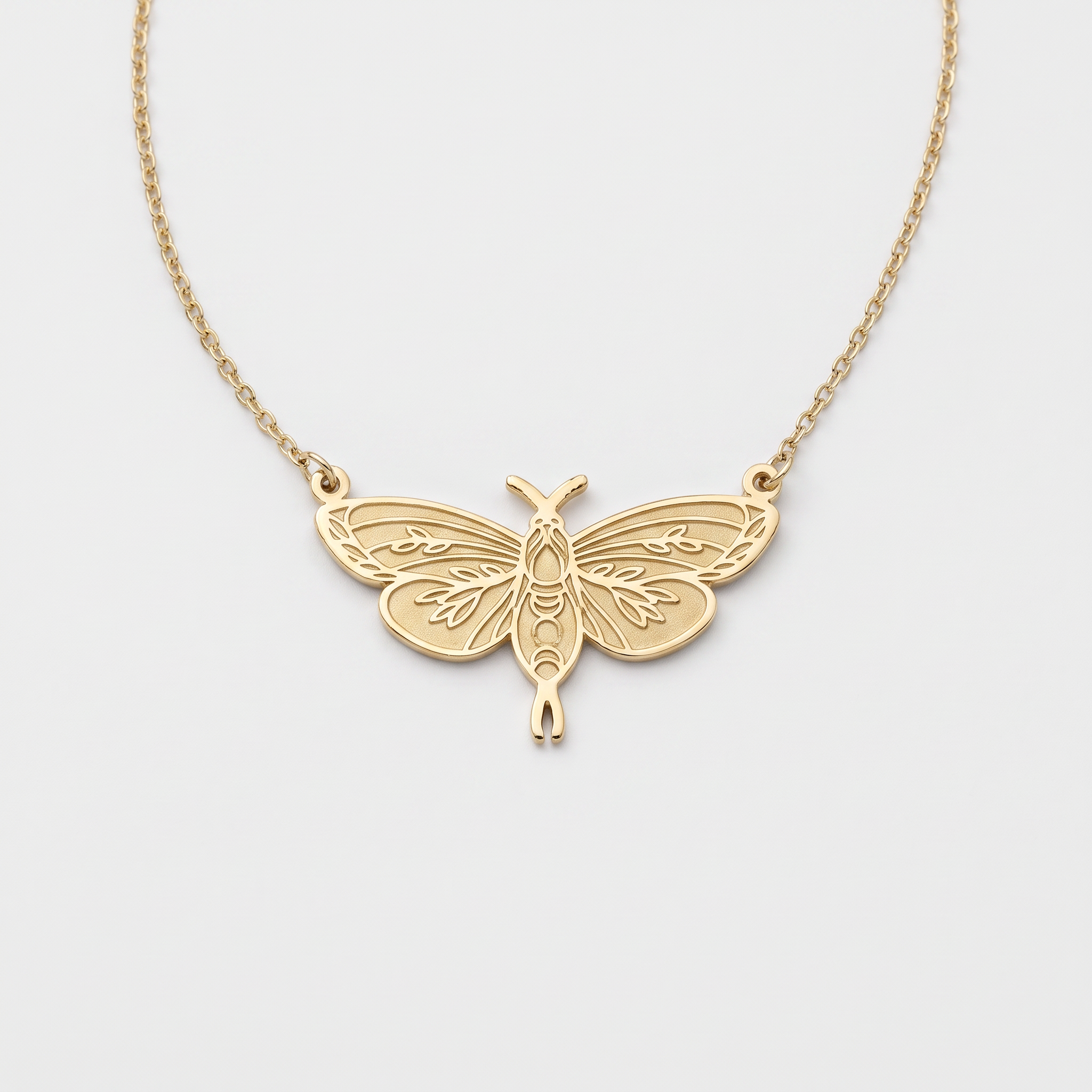 Gold moth necklace with leaf-engraved wings and moon phase body, a moth pendant on a fine cable chain