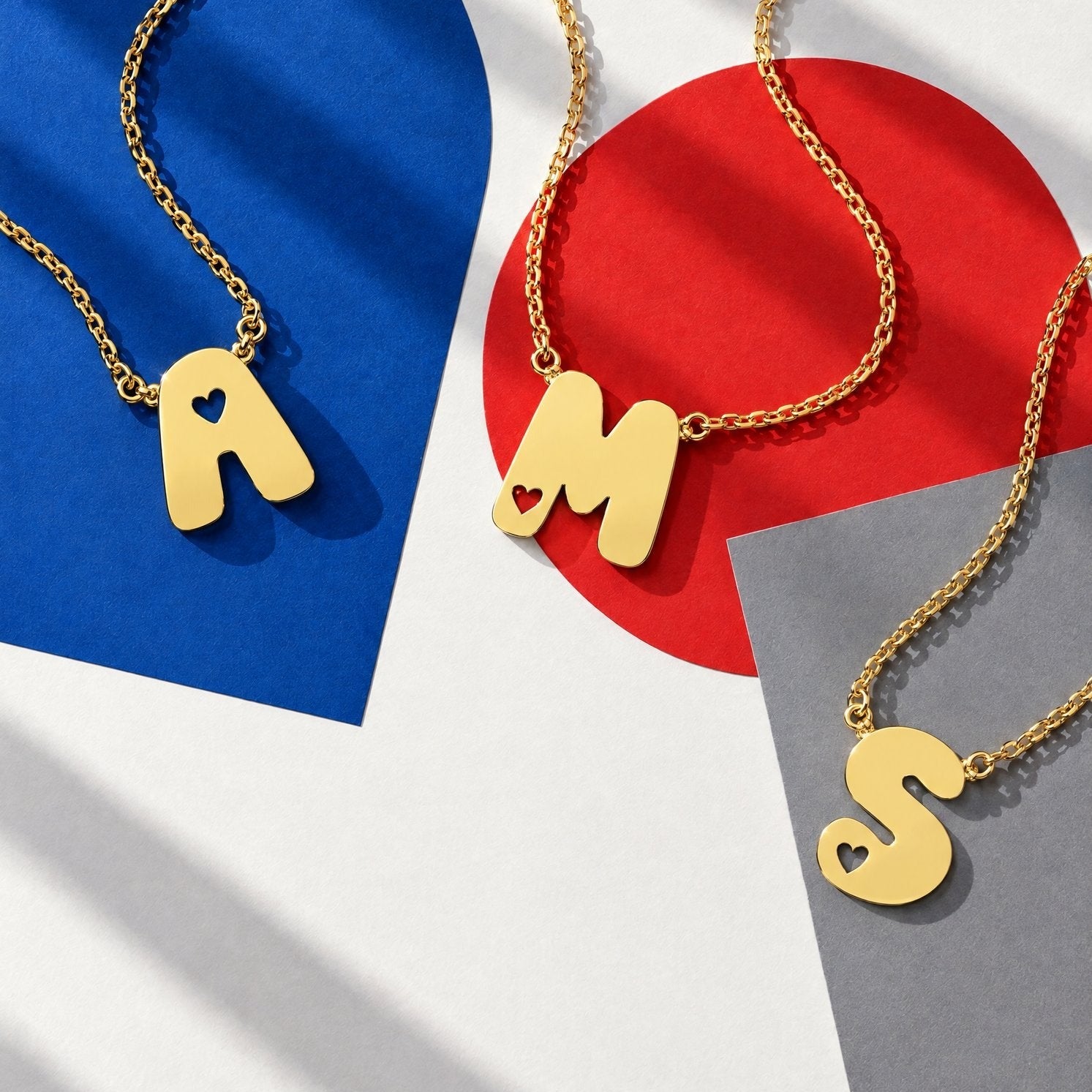 Gold bubble initial necklace with heart cut-out letter pendants A, M and S