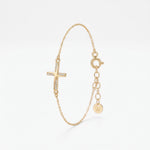 Dainty gold cross bracelet for women with a sideways cross set with cubic zirconia stones, on a fine chain with extender