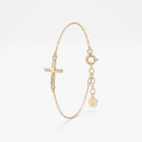 Dainty gold cross bracelet for women with a sideways cross set with cubic zirconia stones, on a fine chain with extender