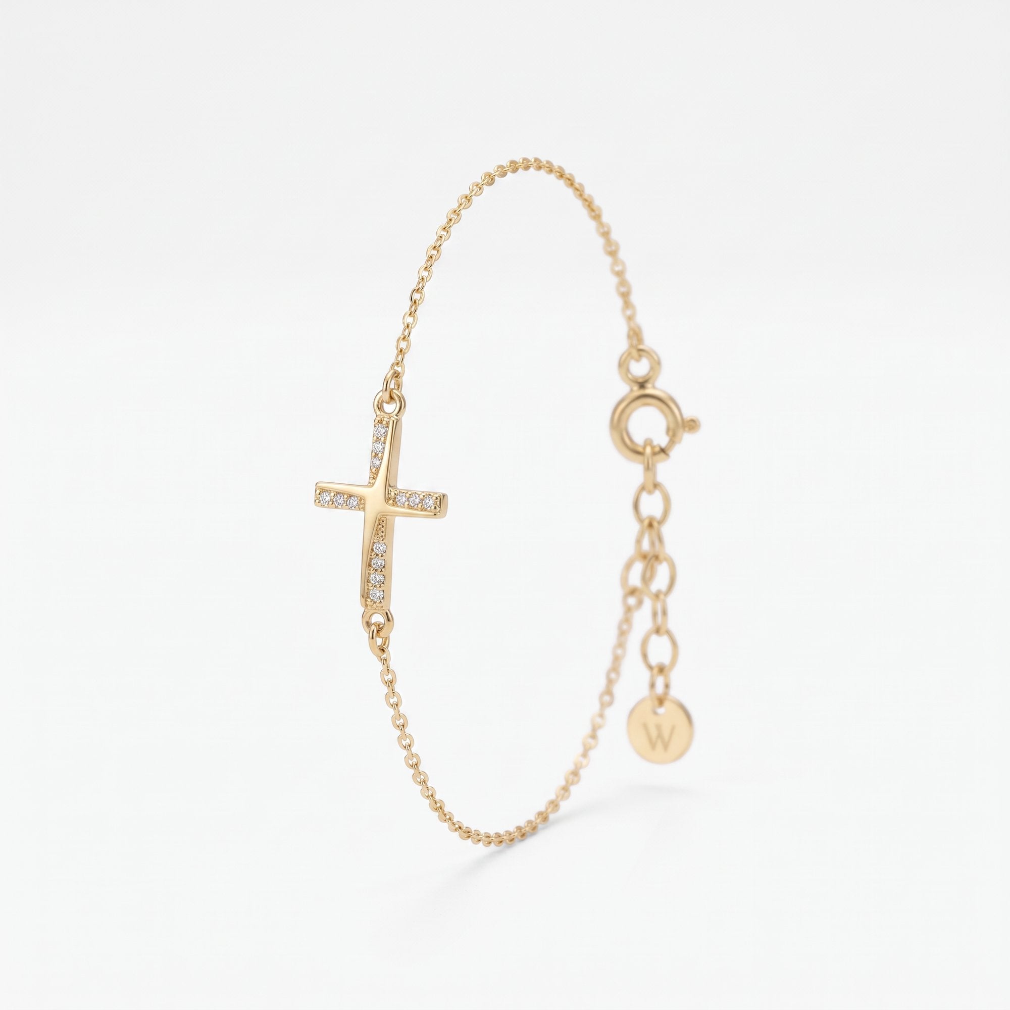 Dainty gold cross bracelet for women with a sideways cross set with cubic zirconia stones, on a fine chain with extender