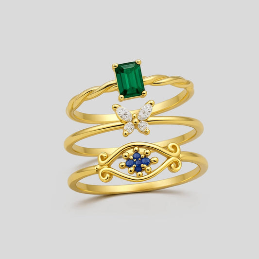 Set of three gold rings with gemstones on a light gray background