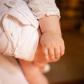 Close-up of a baby&#39;s wrist wearing a gold cross bracelet.