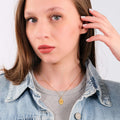 Young woman in grey shirt and denim jacket modeling a 14K Gold Vermeil Bee Pendant Necklace.