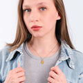 Close-up portrait of a young woman showcasing a 14K Gold Vermeil Bee Pendant Necklace under natural light.