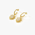 A pair of 14K gold vermeil moonstone earrings displayed on a plain white background, each earring showcasing a moonstone set in a detailed sunburst gold frame hanging from a golden hoop.