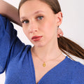 Young woman in a blue sweater looking at the camera, her 14K gold vermeil owl necklace visible.