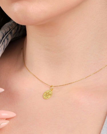 Close view of a 14K gold turtle necklace worn by a woman with a denim jacket, focusing on the necklace.