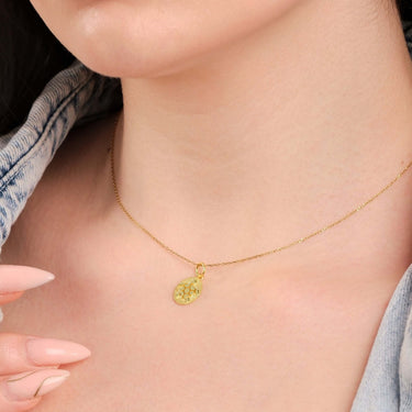 Close view of a 14K gold turtle necklace worn by a woman with a denim jacket, focusing on the necklace.