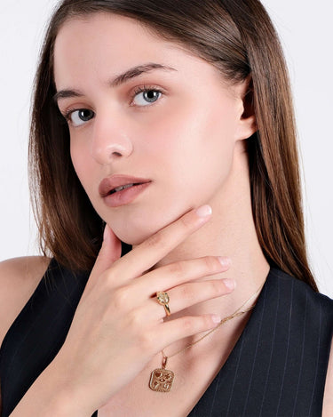 Woman wearing a gold Ouroboros thumb ring and a matching necklace, posing with her hand near her face.