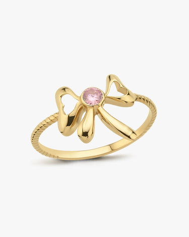 The Mionza Bow Ring, crafted in 14K solid gold, showcases a delicate bow design with a central small, round pink gemstone. The textured ring band features subtle ridges, adding an intricate touch to this elegant piece—perfect for symbolizing love and commitment.