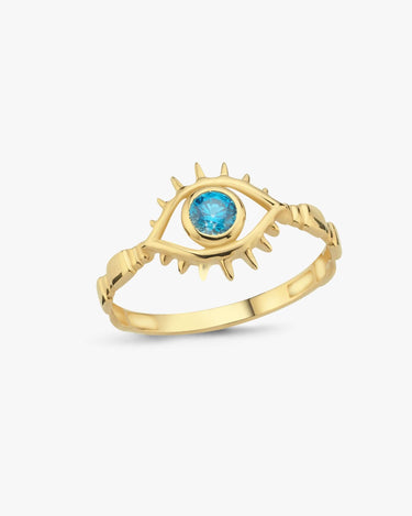 A gold ring featuring a spiky eye design with a blue gemstone at the center, displayed against a plain white background.