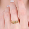 Close-up of a hand wearing a gold bee ring with a honeycomb pattern.