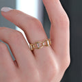 A hand with neatly manicured nails wearing Mionza's dainty Chain Ring in 14K solid gold, featuring two interlocking oval links embedded with diamonds, set against a blurred background.