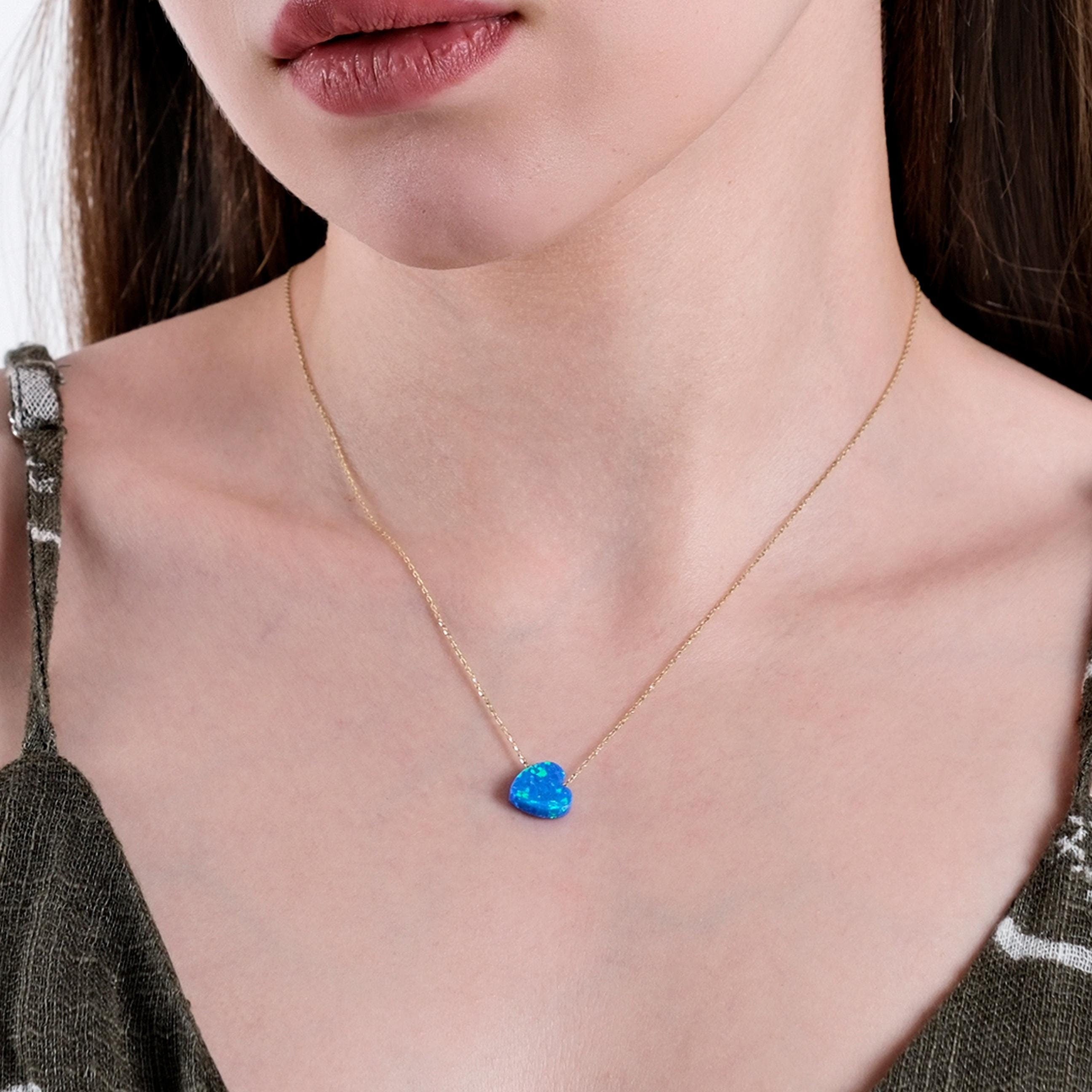 Close-up of a woman's neck showcasing a 14K solid gold necklace with a heart-shaped blue opal pendant.