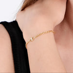 Close-up of a woman's wrist wearing an 18K Gold Vermeil Evil Eye Curb Chain Bracelet, with a delicate chain and a small eye-shaped charm featuring a sparkling gem.