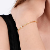 Close-up of a woman's wrist wearing an 18K Gold Vermeil Evil Eye Curb Chain Bracelet, with a delicate chain and a small eye-shaped charm featuring a sparkling gem.