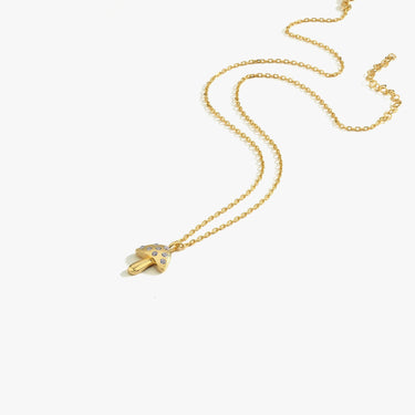 Studio shot of a solitary 18K gold vermeil mushroom necklace, laid flat on a white background.