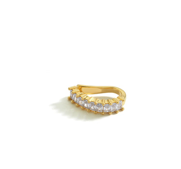 A gold ear cuff with baguette-cut clear stones, shown against a white background. The cuff is designed to fit snugly around the upper ear with a sleek, curved band.