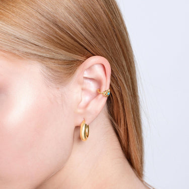 Close-up of a woman&#39;s ear with a gold vermeil evil eye ear cuff featuring a turquoise stone, worn on the upper ear with a gold hoop earring below