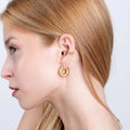 Side profile of a woman wearing a gold hoop earring and a gold vermeil evil eye ear cuff with a turquoise stone on the upper part of her ear