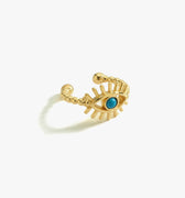 Gold vermeil ear cuff in the shape of an eye with a turquoise stone at the center, displayed on a white background.