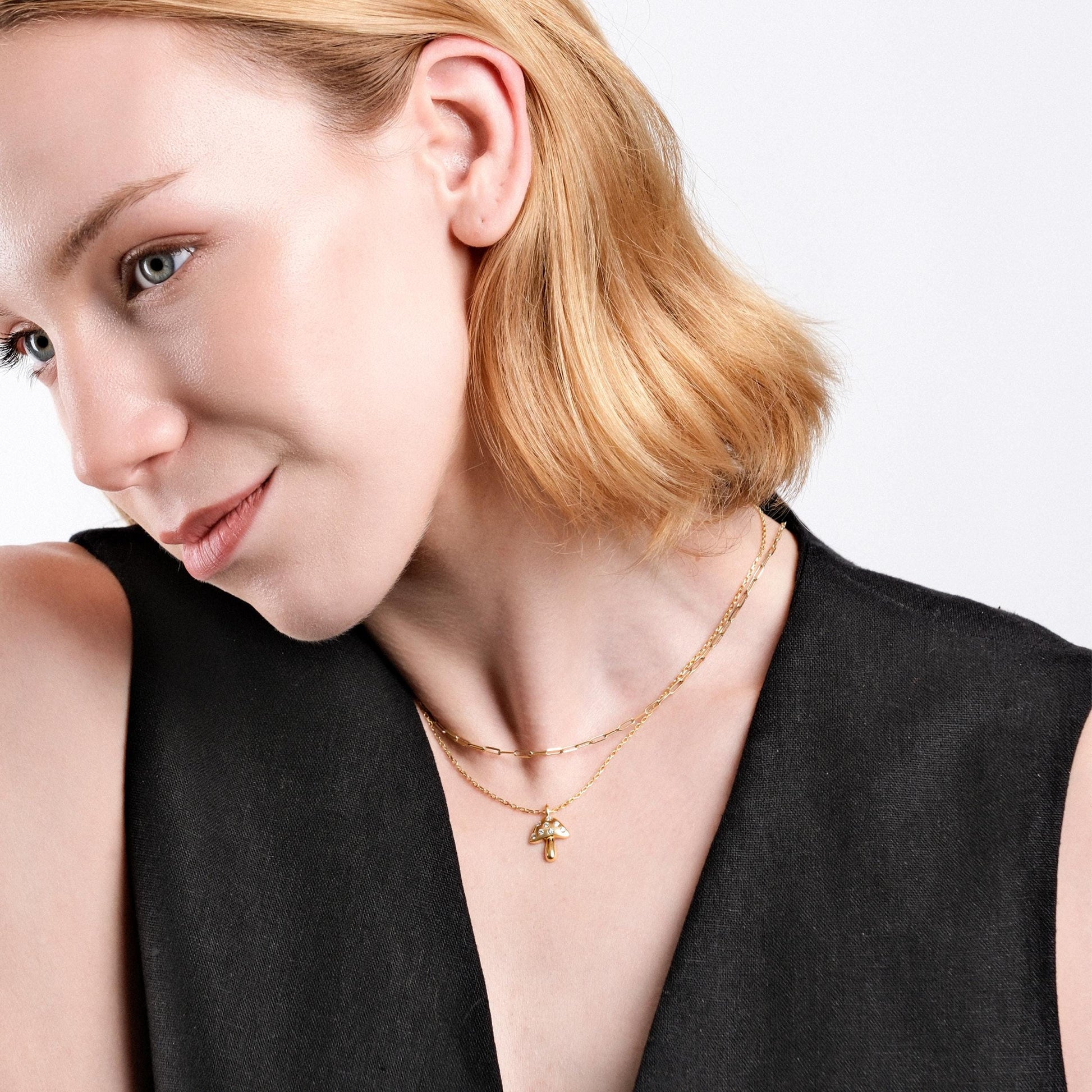 She showcases an 18K gold vermeil mushroom necklace, layered with a thin gold chain.