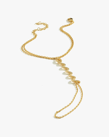 A single gold snake hand chain bracelet with a zigzag design, laid flat against a white background.