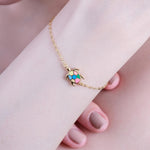 Gold chain bracelet with colorful turtle charm on wrist, showcasing elegant and playful jewelry design.