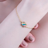 Gold chain bracelet with colorful turtle charm on wrist, showcasing elegant and playful jewelry design.