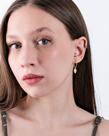 Woman wearing 18K gold vermeil North Star and evil eye earrings.