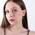 Woman wearing 18K gold vermeil North Star and evil eye earrings.