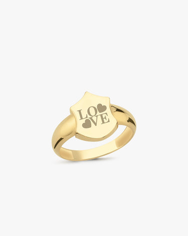 A 14K solid gold initial ring with a shield-shaped face engraved with the word &quot;LOVE&quot; and two heart symbols, displayed on a plain white background.