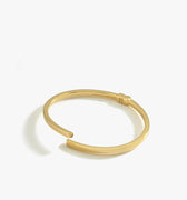 A product shot of the 18K gold vermeil hinged bangle bracelet, displaying its open-ended design on a white background.