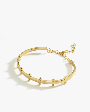 A product image of the 18K gold vermeil station cuff bracelet. The bracelet lies flat against a white background, displaying its curved design with small rounded stations and an adjustable chain closure.