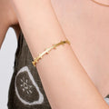 A close-up of a woman&#39;s arm adorned with an 18K gold vermeil station cuff bracelet.