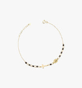 Product image of a 14K solid gold onyx rosary bracelet laid out on a white background. The bracelet features a gold cross and medallion charm, with small black beads interspersed along the chain.