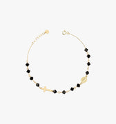 A 14K gold bracelet with black onyx beads, a cross charm, and a small medallion, displayed flat on a white background.