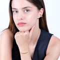 A woman resting her chin on her hand while wearing an 18K Gold Vermeil beaded bracelet, with matching earrings visible.